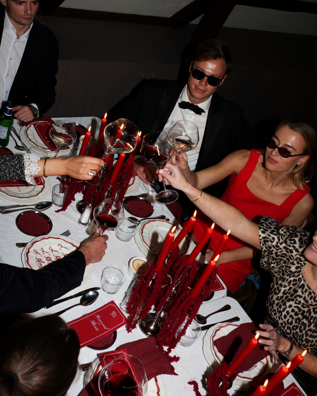 Chez Jules table styling by Imaginary Friends – red candles, scalloped plates, wine glasses and an intimate dinner atmosphere in deep red tones.