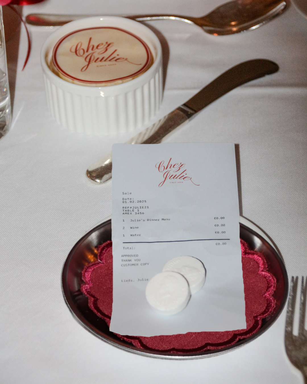 Chez Jules personalized table details – receipt-style menu, butter topper, scalloped plates and deep red styling elements by Imaginary Friends.