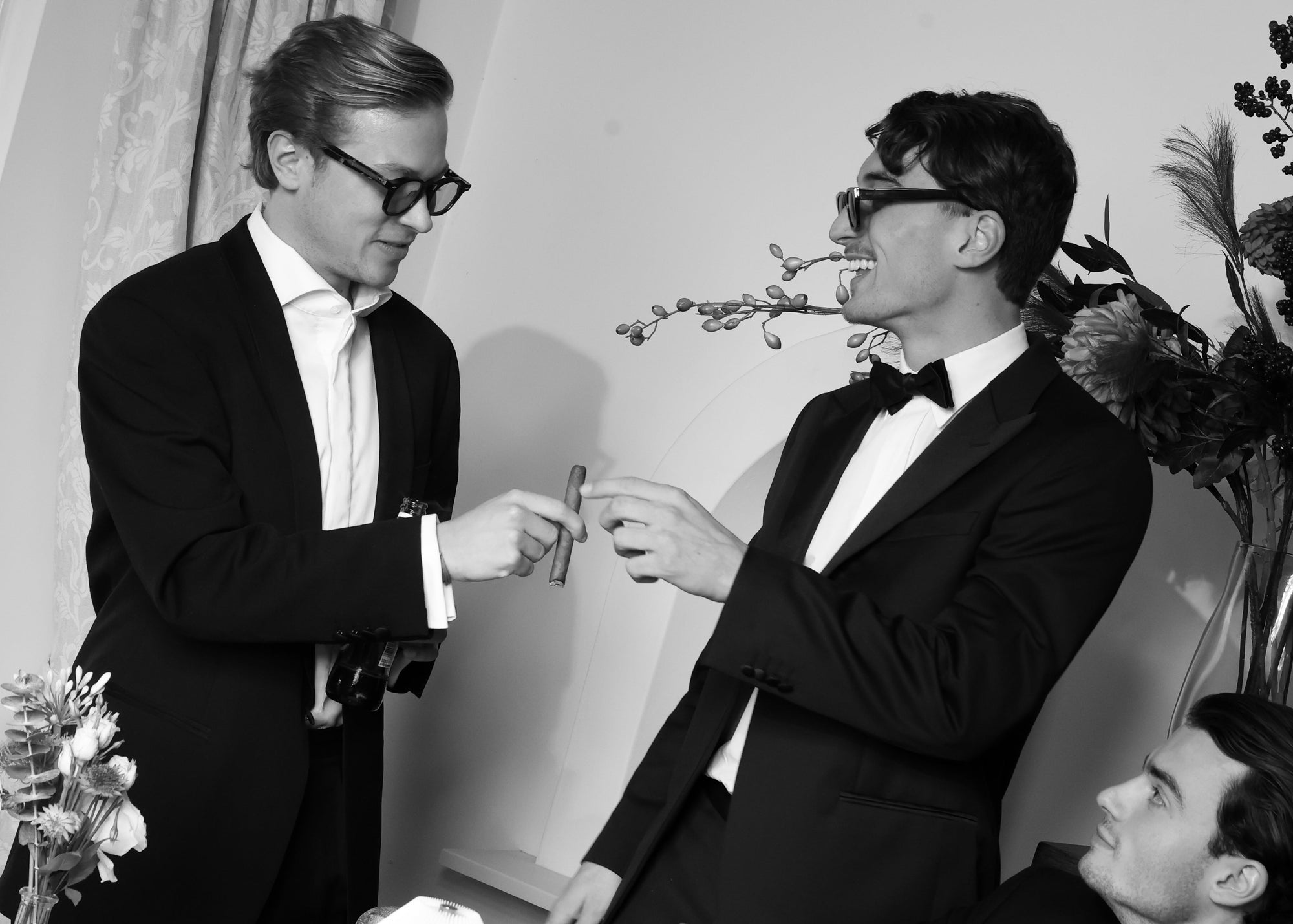 Two men in formal attire toasting at an Imaginary Friends styled dinner table with glassware and soft florals.
